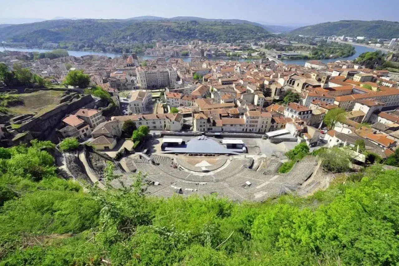 Vue panoramique de l'amphithéâtre romain de Vienne, un site historique majeur, avec la ville et le Rhône en arrière-plan. L'école de Vienne, un lieu d'apprentissage et de culture, s'intègre dans ce paysage.