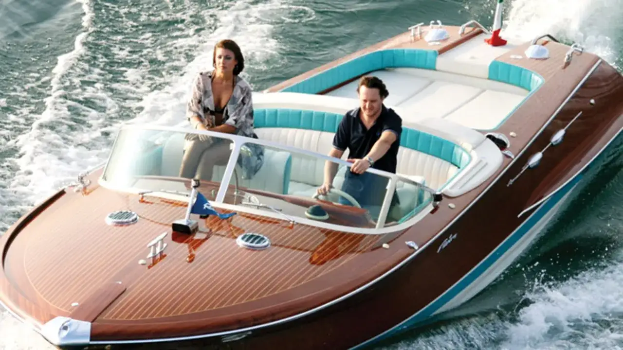 Un uomo guida una barca di lusso in legno, simile a quelle che amava Gianni Agnelli, con una donna seduta al suo fianco.