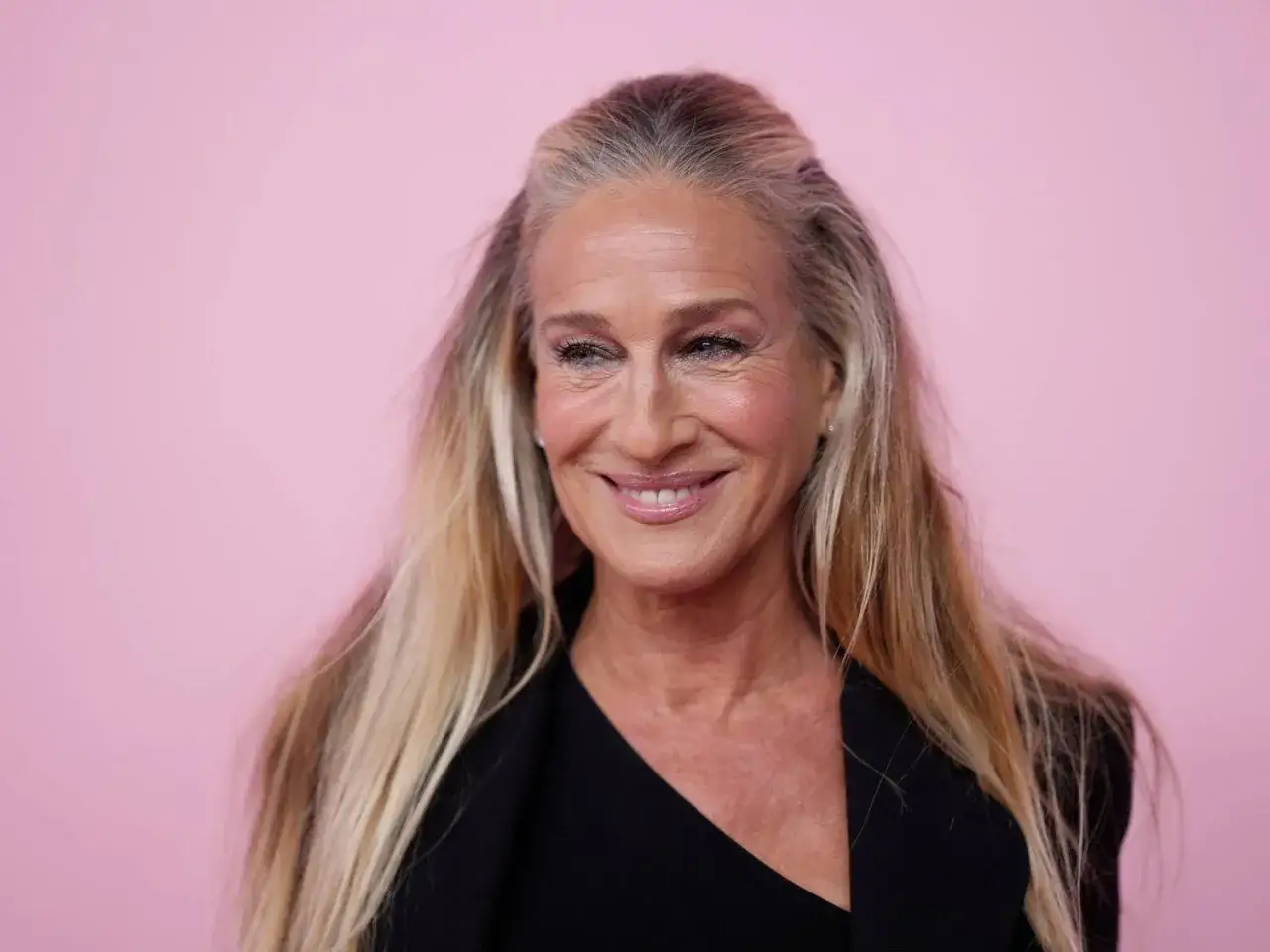 Sarah Jessica Parker ler, hennes långa hår har vackra slingor i grått hår som blandas med blont.