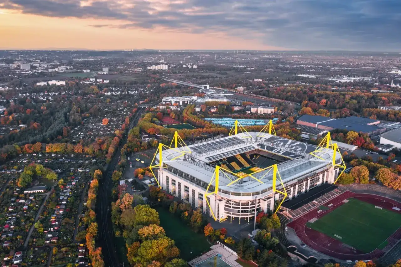 Widok z lotu ptaka na Signal Iduna Park, stadion w Dortmundzie, otoczony jesienną zielenią.