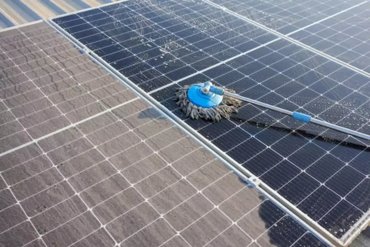 Limpieza de placas solares sucias con un mocho. La mitad de los paneles est&aacute;n limpios y brillantes, la otra mitad cubiertos de polvo.