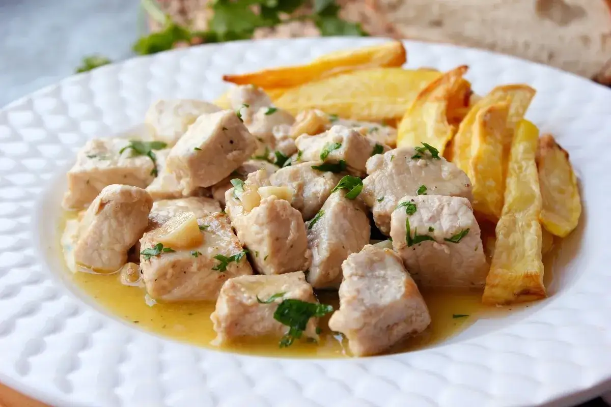Sabroso lomo al ajillo en trozos, ba&ntilde;ado en aceite y ajo, acompa&ntilde;ado de patatas fritas crujientes.