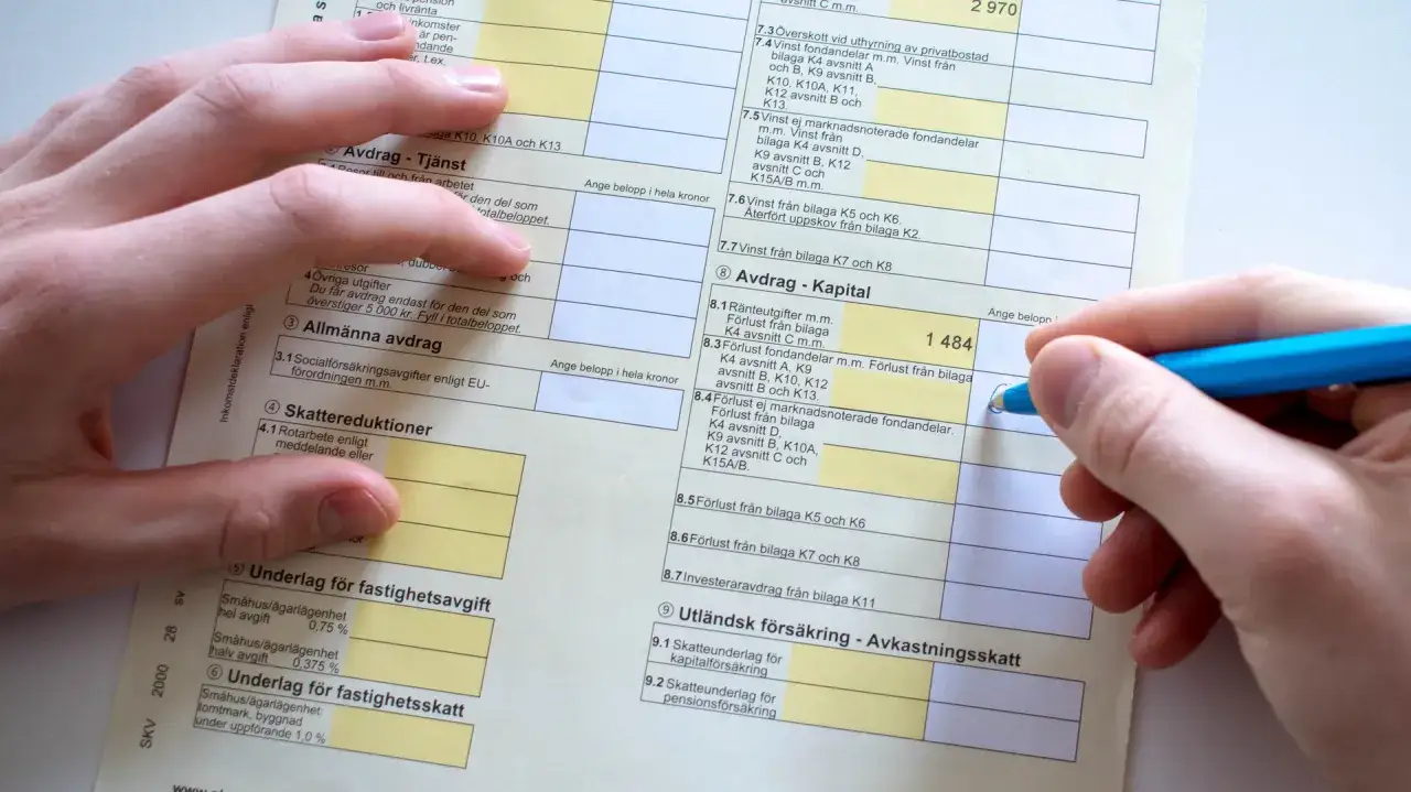 Här ser du hur man deklarerar. En hand fyller i en blankett med siffror och text.