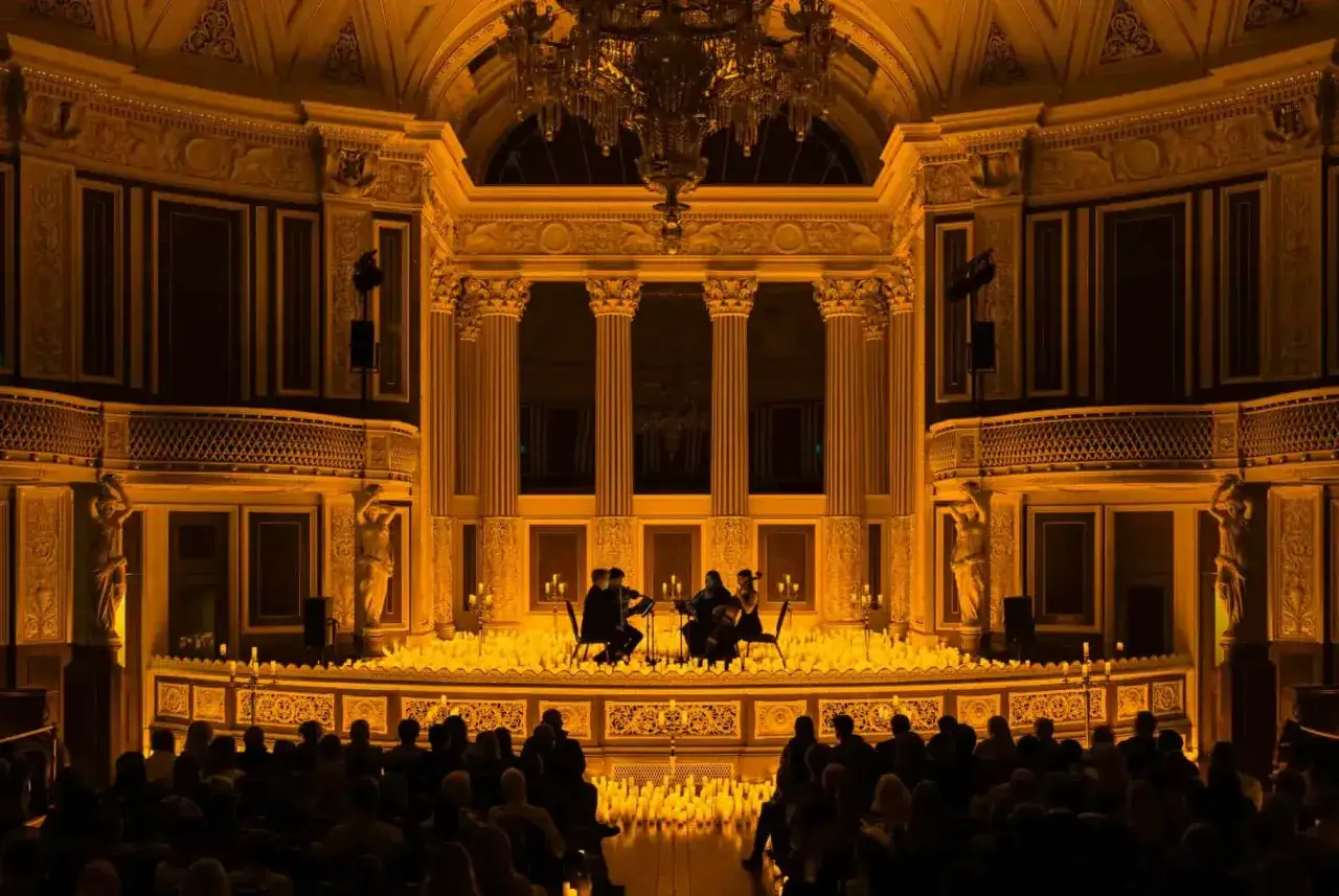 Un concierto de m&uacute;sica cl&aacute;sica con un ambiente de **candlelight el se&ntilde;or de los anillos**. Un tr&iacute;o de cuerdas toca en un escenario iluminado por miles de velas.