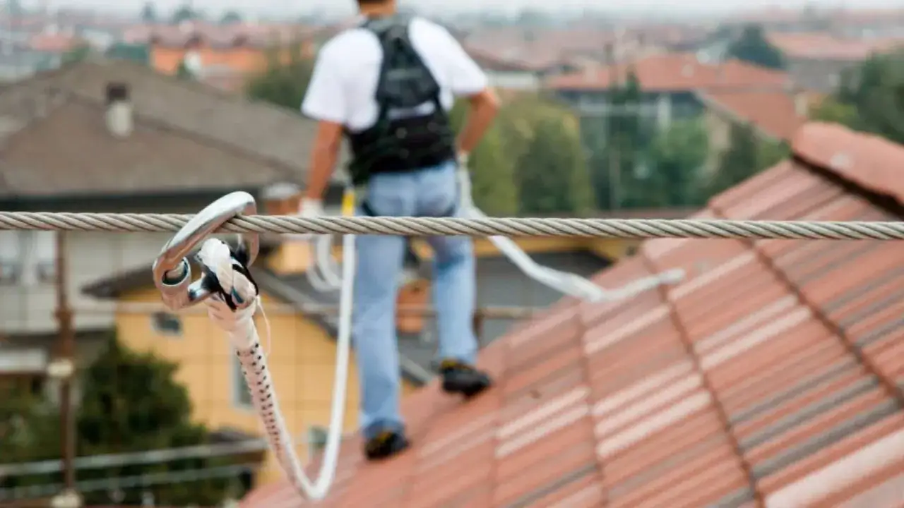 Operaio su tetto con imbracatura collegata alla linea vita tetto obbligatoria, per garantire la sicurezza durante i lavori.