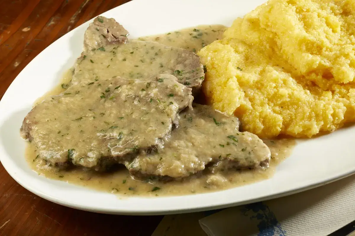 Fettine di vitello in salsa con polenta, un classico della ricetta bresciana.
