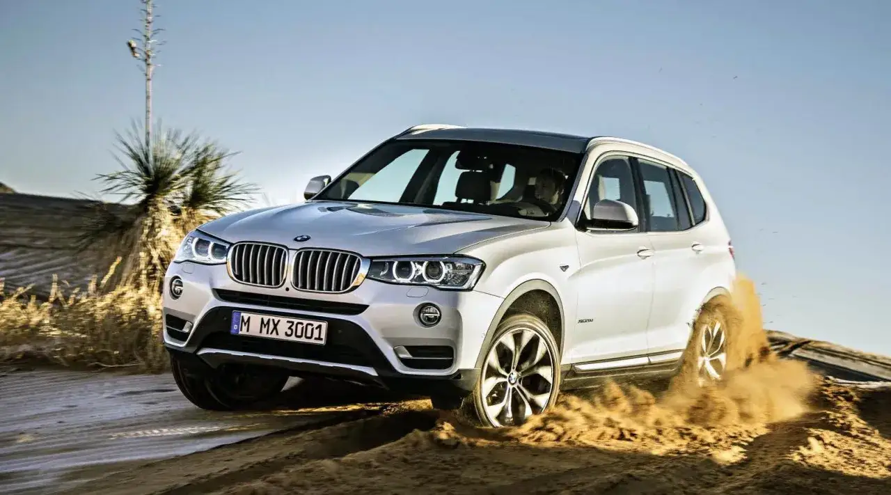 Vit BMW X3 k&ouml;r i sanden, hjulen slirar. Ett potentiellt BMW X3 problem med greppet i terr&auml;ngen.