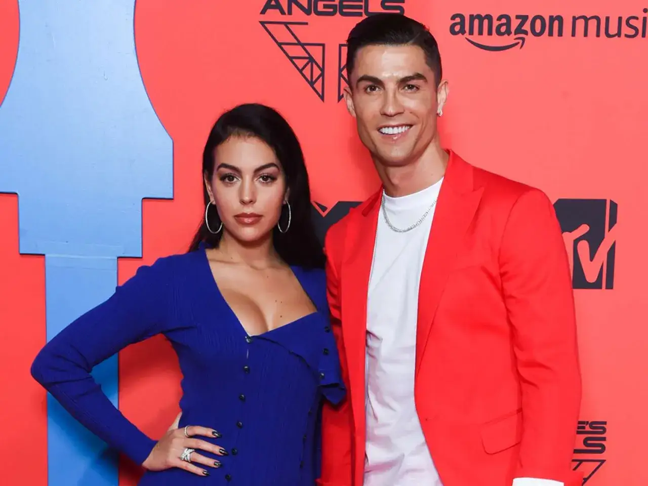 Cristiano Ronaldo i jego partnerka, Georgina Rodríguez, na czerwonym dywanie. Ona w niebieskiej sukience, on w czerwonej marynarce.
