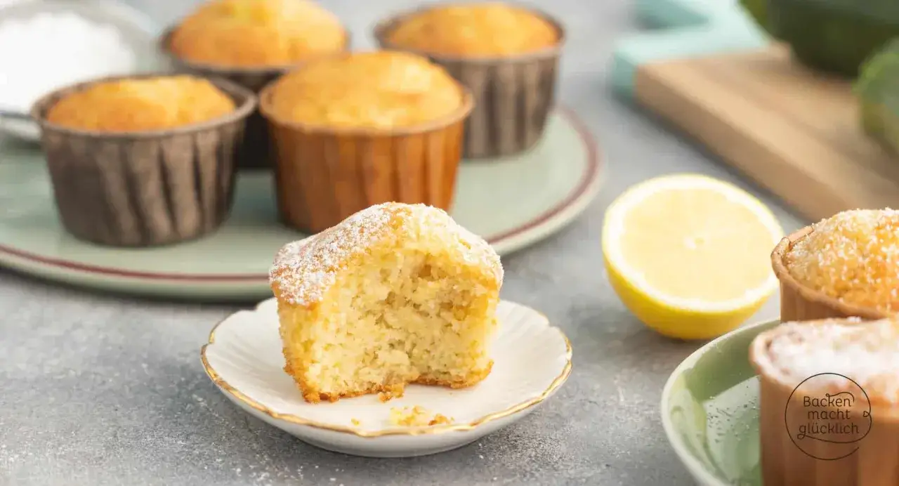 Saftige zucchini muffins, best&auml;ubt mit Puderzucker, neben einer Zitrone.