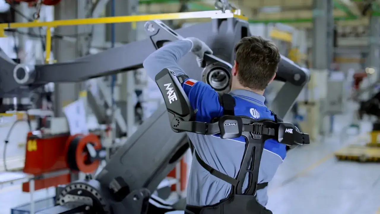Un ouvrier utilise un exosquelette pour soulever une pi&egrave;ce lourde. C'est une aide m&eacute;canique qui amplifie la force humaine, une v&eacute;ritable exosquelette d&eacute;finition pour l'industrie.