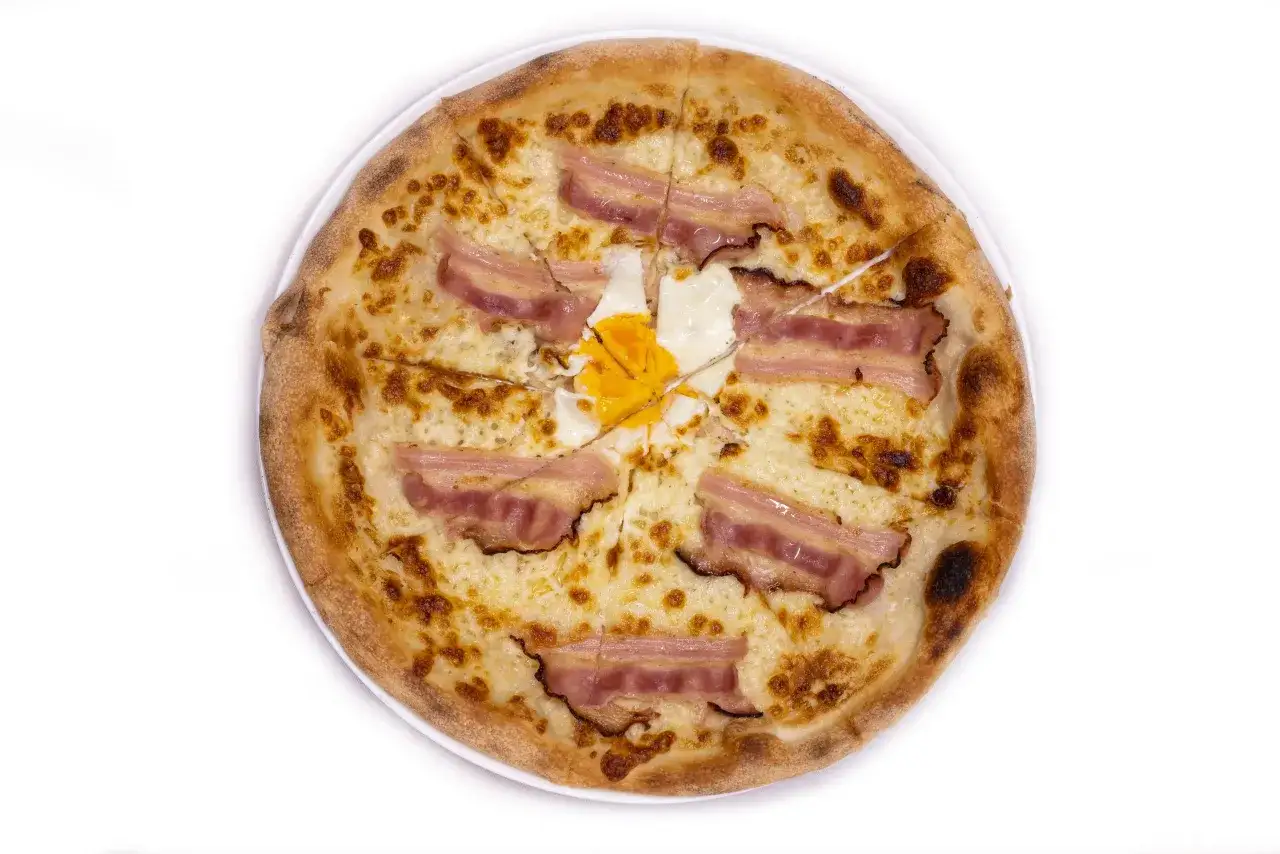 Pizza carbonara z chrupiącym boczkiem i jajkiem sadzonym na wierzchu.
