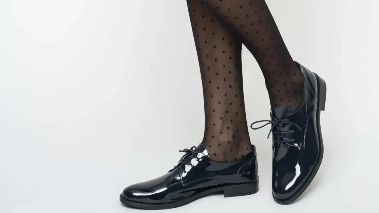 Pieds chaussés de derbies femme vernies et collants à pois. Un look chic et moderne pour savoir comment porter des derbies femme.