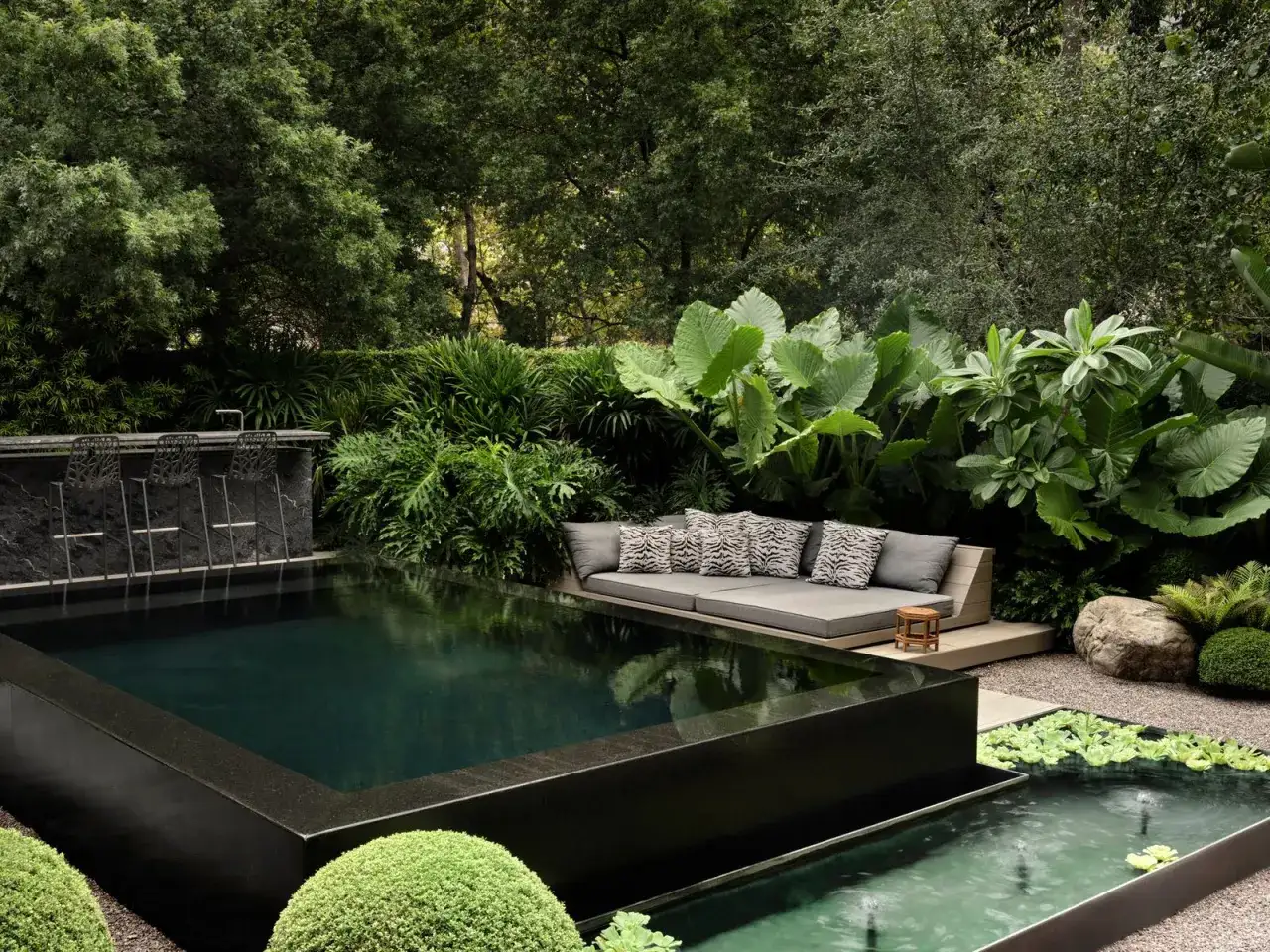 Un espace ext&eacute;rieur luxuriant avec une piscine sombre, un bar et un canap&eacute; invitant. Le bienfait jacuzzi est palpable dans cette oasis de d&eacute;tente.