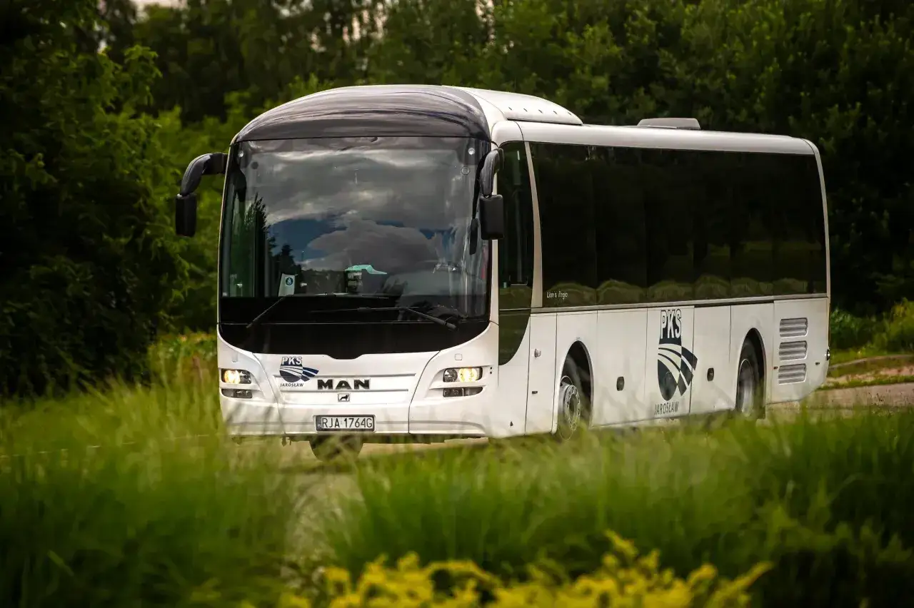 Biały autobus PKS z Jarosławia jedzie przez zielony krajobraz, być może w drodze do Horyńca-Zdroju.