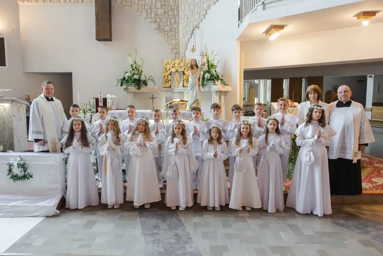 Dzieci w bieli przy ołtarzu. Czy można przyjąć komunię świętą dwa razy w ciągu dnia? Pytanie to nurtuje wielu wiernych.