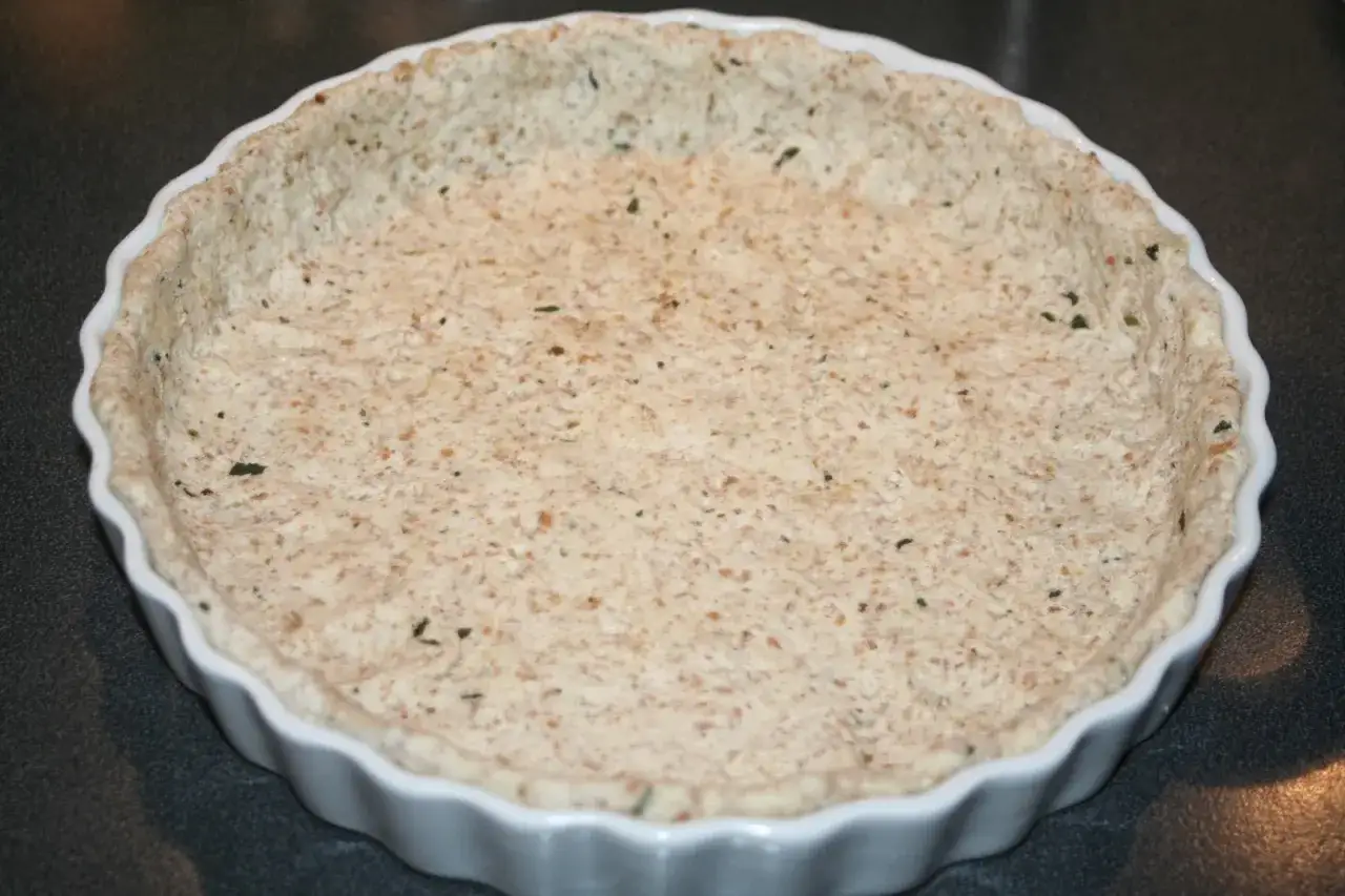 En färdigbakat pajskal i en vit form, redo för fyllning. Ett perfekt steg i ett paj recept.