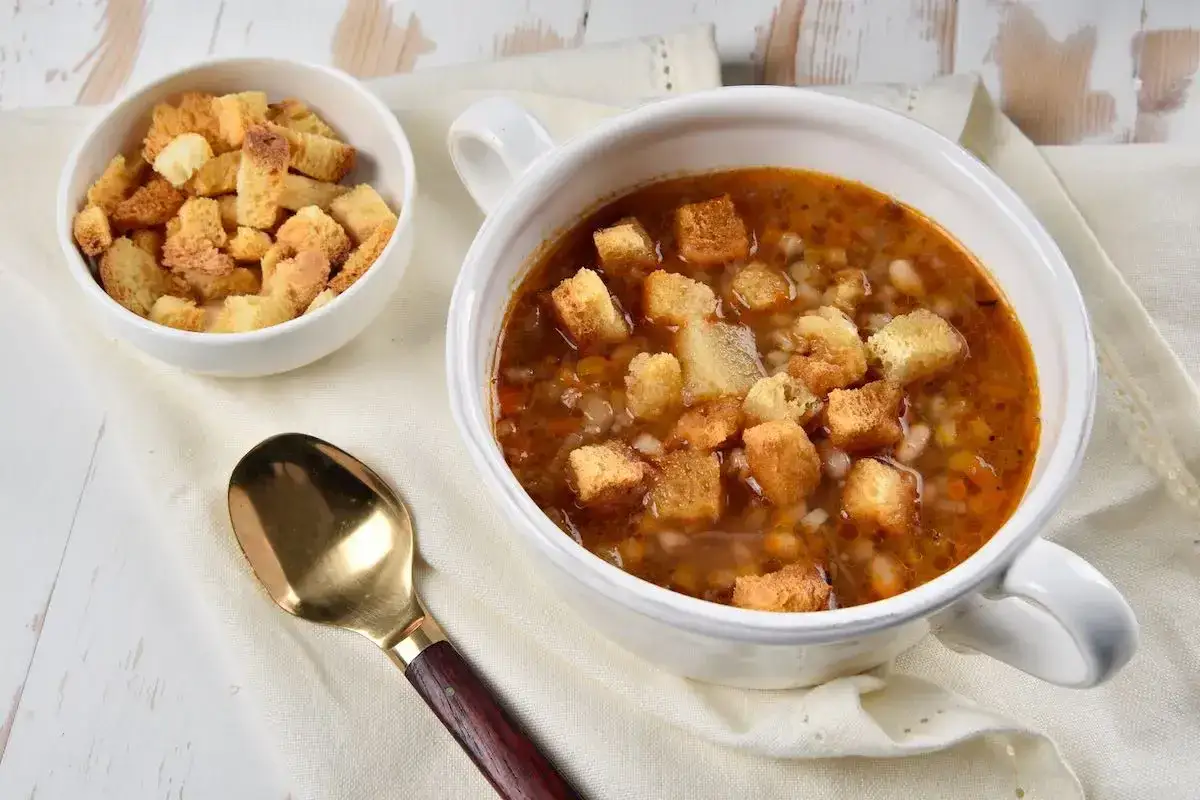Minestra di fagioli e orzo fumante in ciotola con crostini