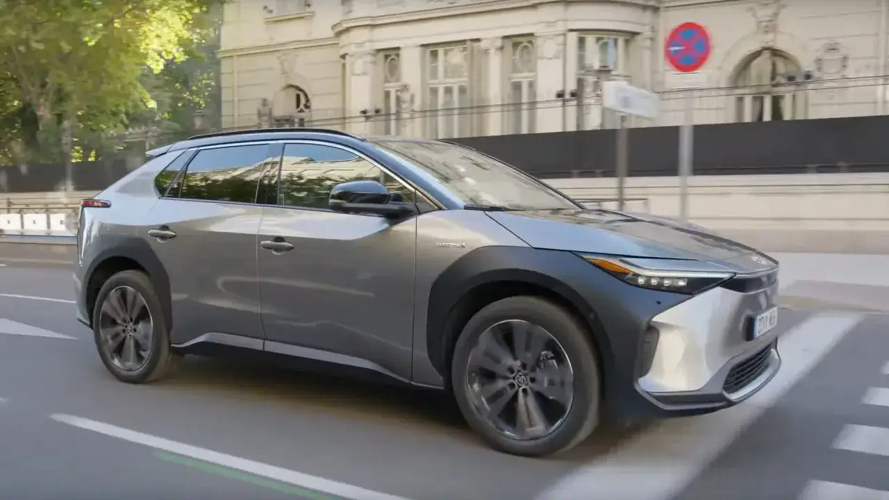 Szary Toyota bz4x testowy przejeżdża przez miejskie skrzyżowanie.