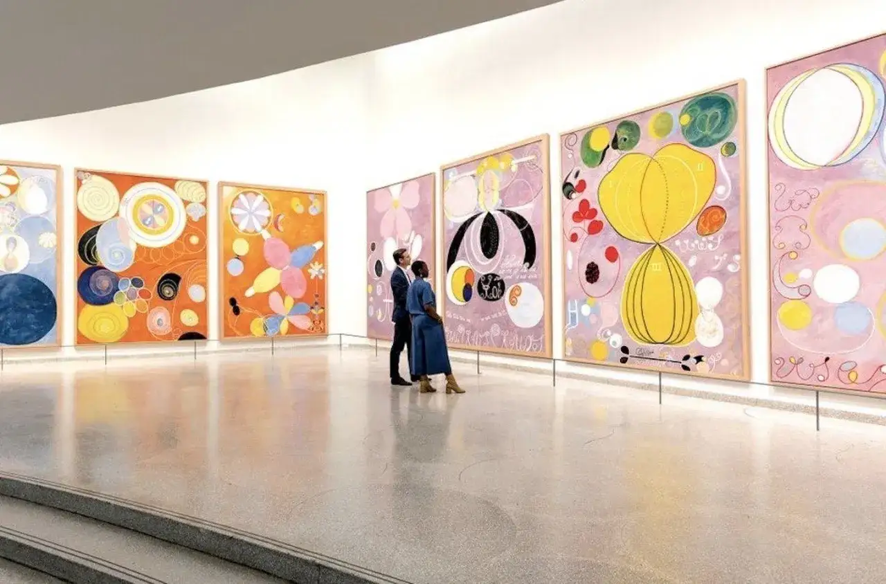 Zwei Personen betrachten farbenfrohe Werke des arte moderno in einer Galerie.