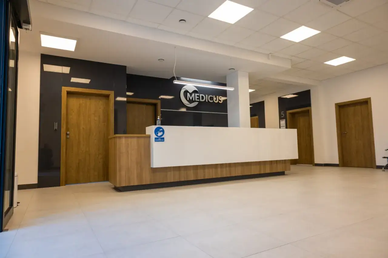 Nowoczesne centrum medyczne z recepcją, logo Medicus i drewnianymi drzwiami.