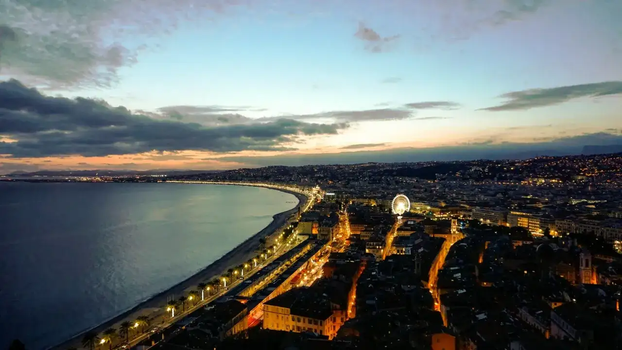 Zachód słońca nad Niceą w grudniu. Promenada, morze i rozświetlone miasto z diabelskim młynem.