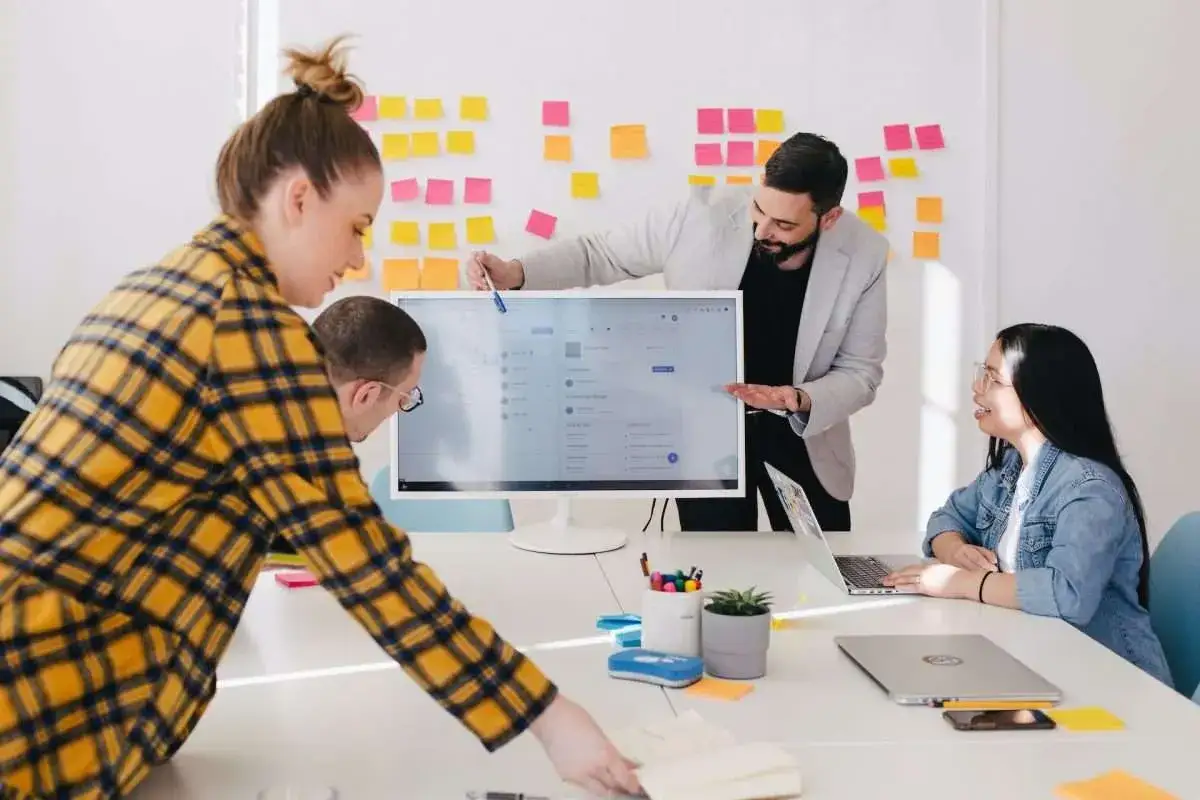 Equipo colaborando en ideas para los mejores negocios online. Un hombre señala la pantalla, mientras otros observan y toman notas.