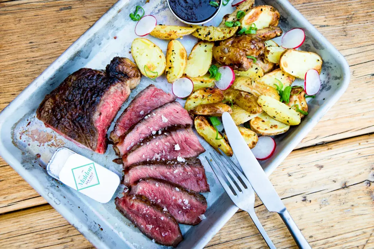 Idealny stek na grillu, soczysty i krwisty, podany z pieczonymi ziemniakami i rzodkiewką. Idealny sposób, jak zrobić steka na grillu.