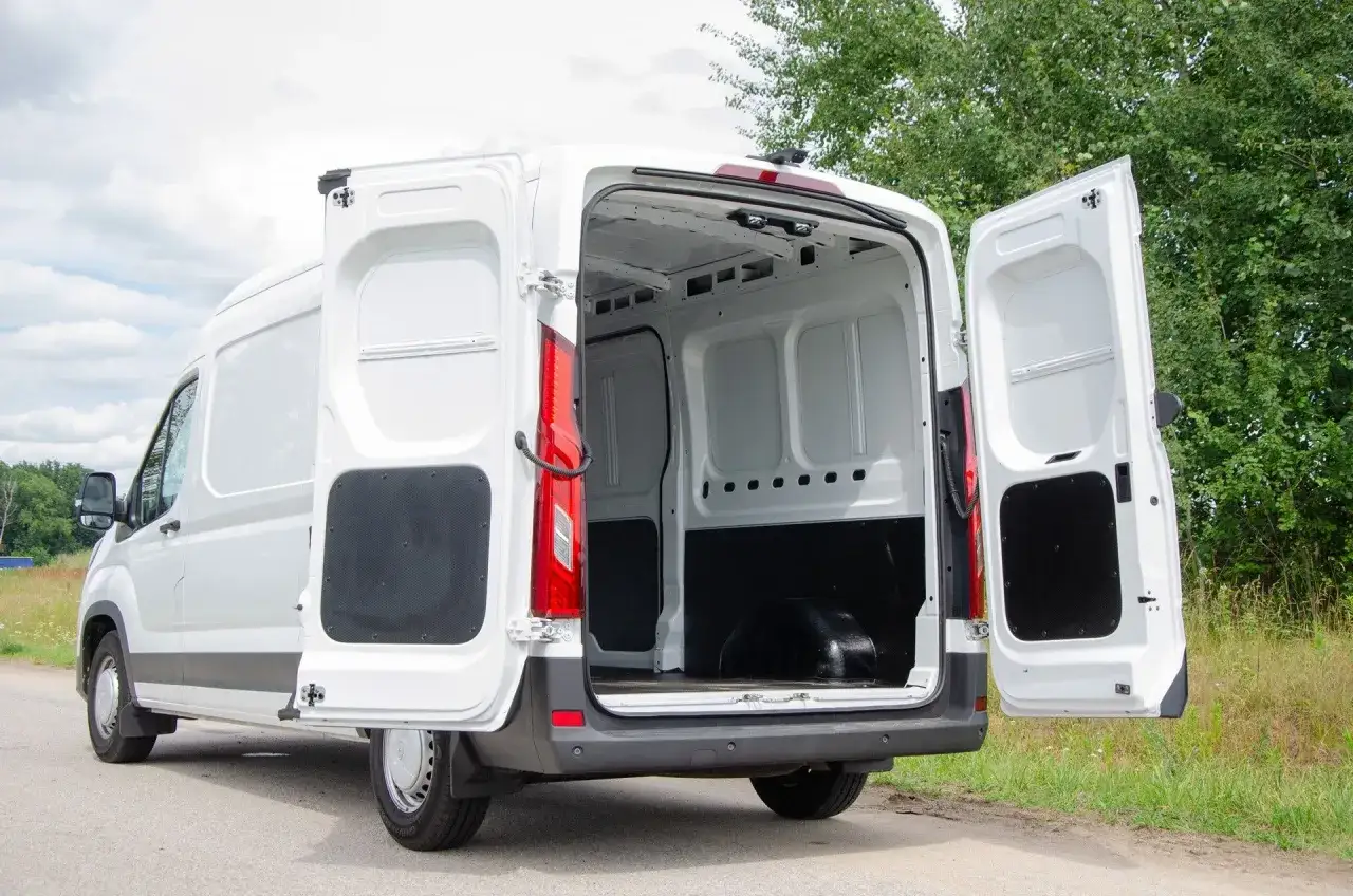 Biały Maxus Deliver 9 z otwartymi drzwiami bagażnika i bocznymi, gotowy do załadunku.