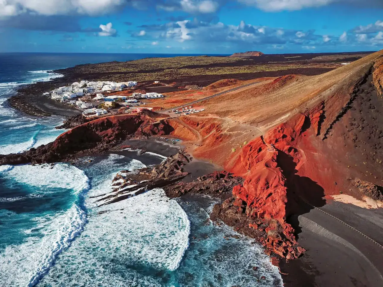 Vista aérea de El Golfo, Lanzarote. El verde de la laguna contrasta con las rocas rojas y el mar azul. Imprescindible entre las cosas que ver en Lanzarote.