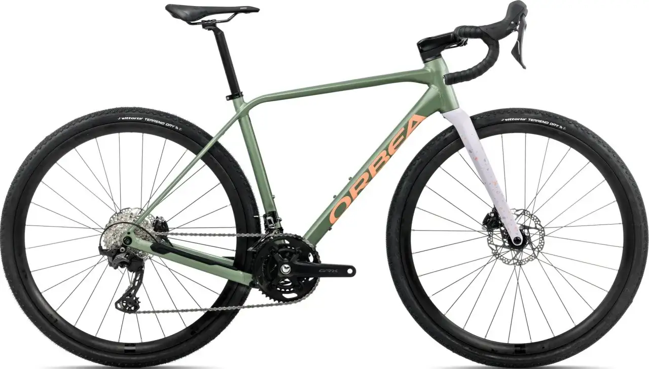 Zielony rower gravel turystyczny Orbea z pomarańczowym logo, gotowy na przygodę po szutrowych drogach.