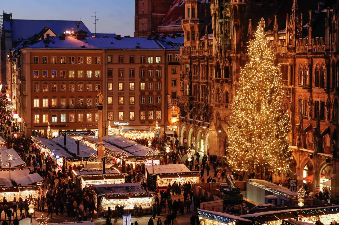 A bustling Christmas market in Munich, Germany, with a giant, illuminated tree and snow-dusted stalls.