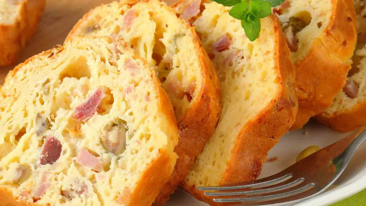 Tranches d'un cake jambon olive, garni de morceaux de jambon et d'olives vertes, pr&ecirc;t &agrave; &ecirc;tre d&eacute;gust&eacute;.