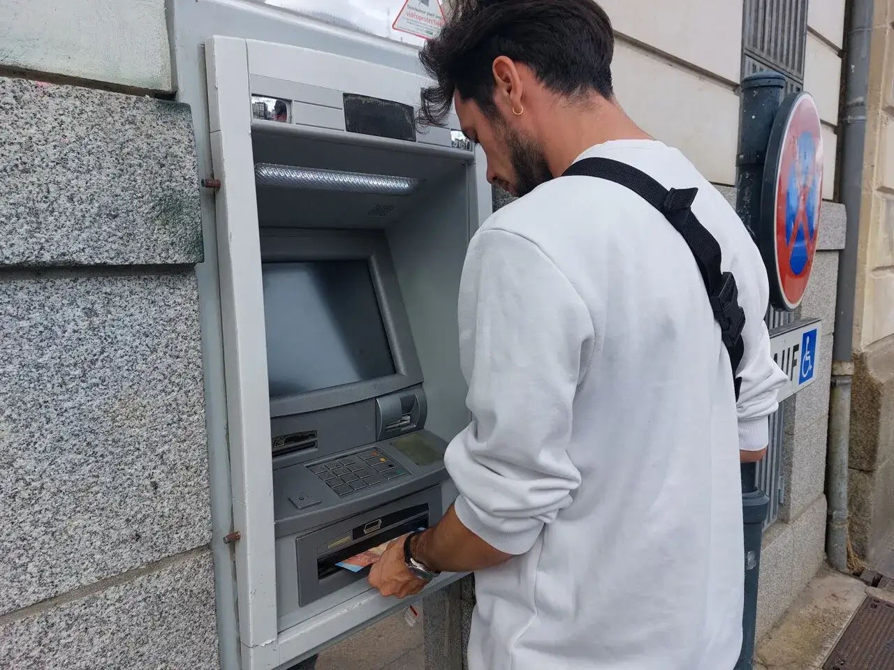Un homme retire de l'argent à un distributeur automatique. Il suit les étapes pour comment retirer de l'argent.