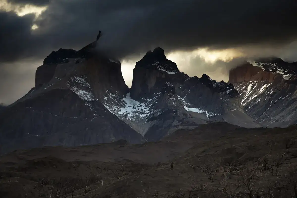 Un homme solitaire, Mathieu Le Lay, marche dans un paysage d&eacute;sol&eacute; sous des montagnes sombres et mena&ccedil;antes.