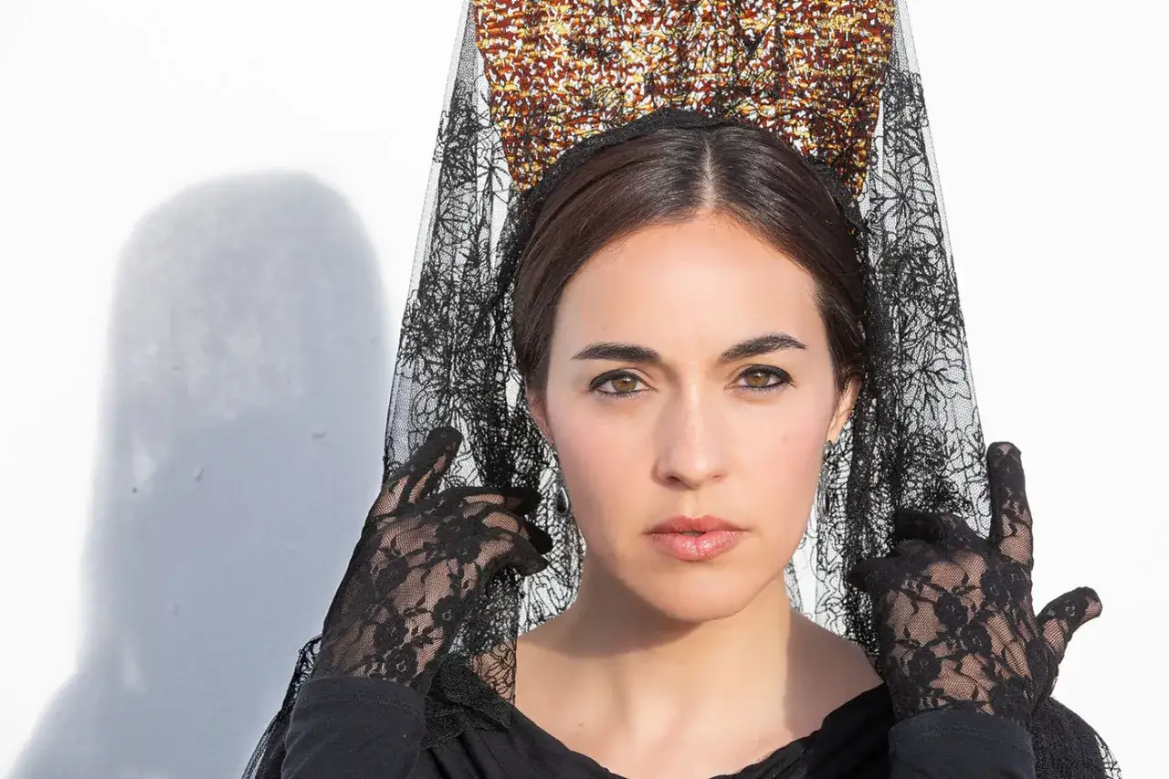 Mujer con peineta y mantilla negra de encaje, guantes a juego. Aprende como poner peineta y mantilla para un look tradicional.