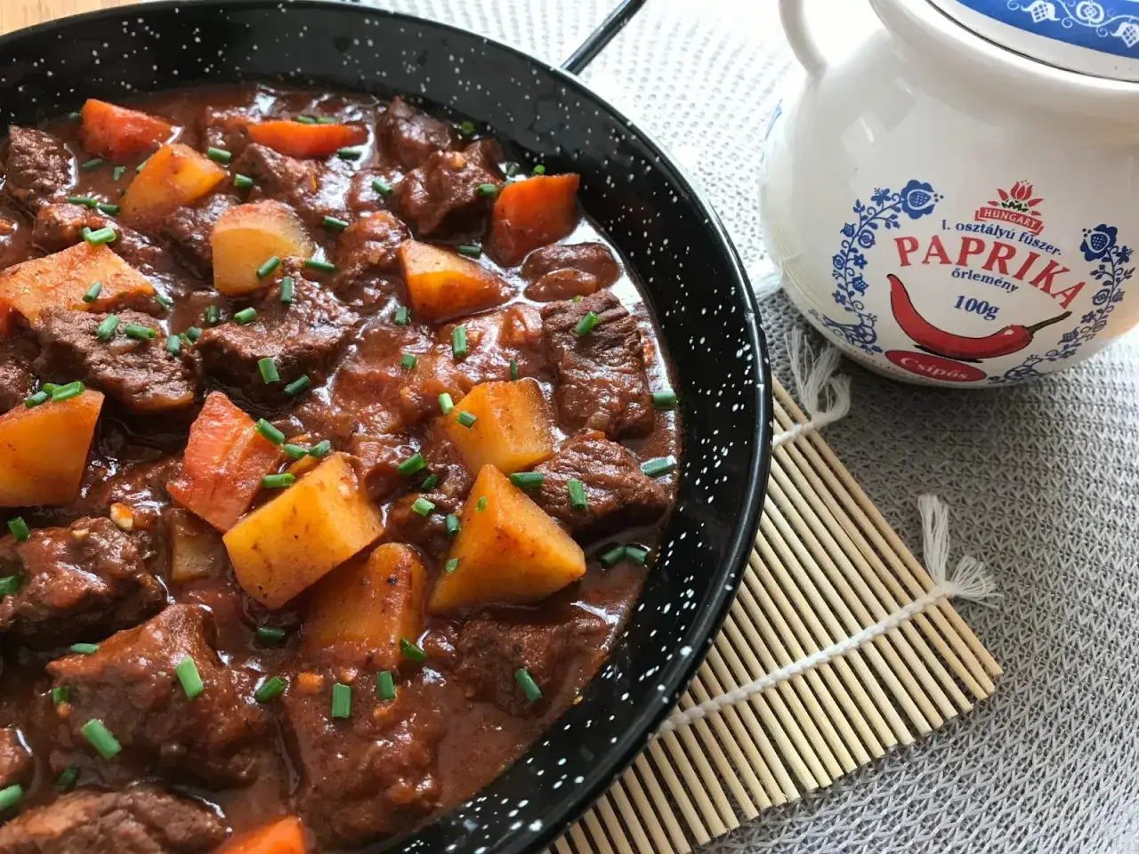 Goulash de ternera, un plato reconfortante con trozos de carne tierna, patatas y zanahorias en una rica salsa, espolvoreado con cebollino fresco.