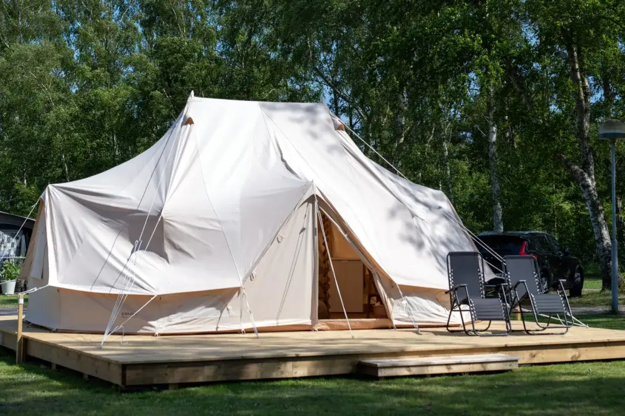 Stor glampingtält på träaltan, redo för camping i Gnesta. Två solstolar står framför tältet.