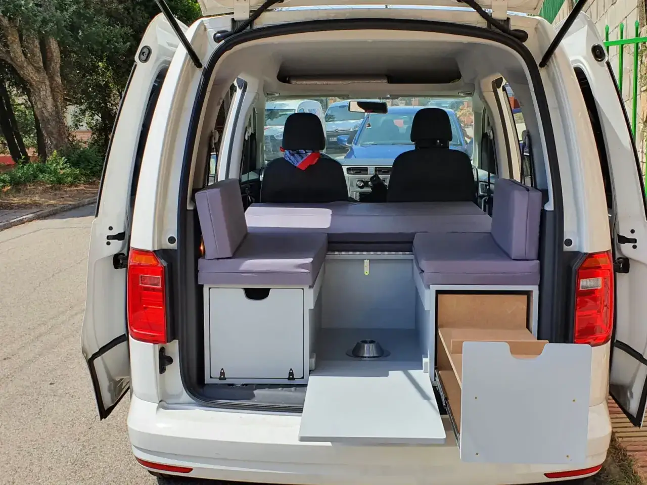Aménagement intérieur d'un caddy tramper prêt pour l'aventure. Deux sièges avant, un lit confortable et des rangements astucieux.