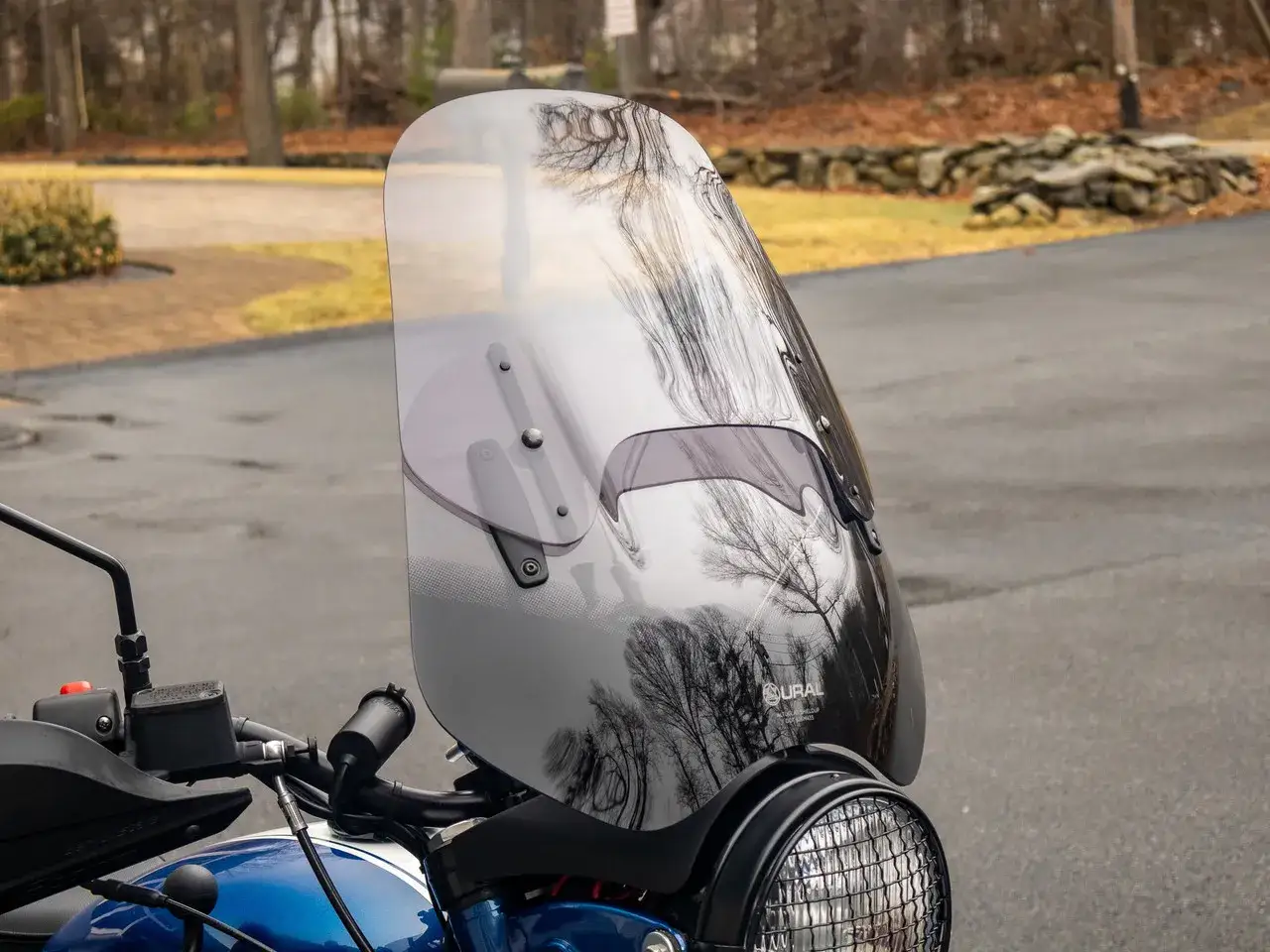 Manubrio e parabrezza di una moto, perfetta per la moto per citt&agrave; e viaggi. Riflessi di alberi sul parabrezza.