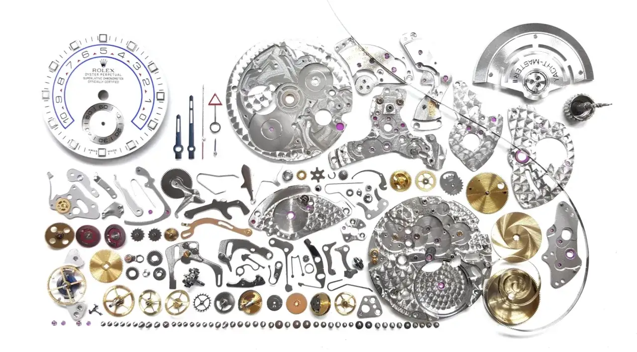 Despiece de un mecanismo reloj de lujo, con esfera Rolex, engranajes, puentes y espiral.