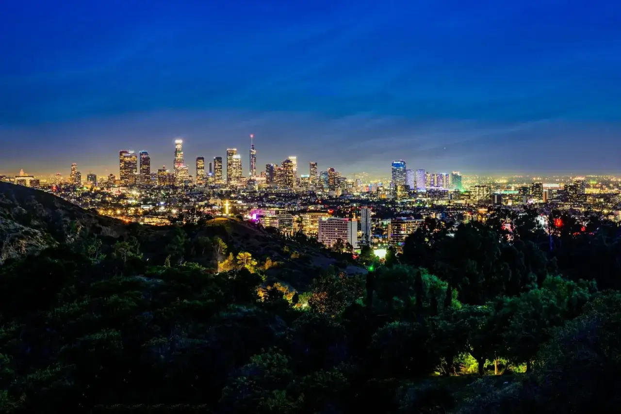 Nocny krajobraz Los Angeles z oświetlonymi wieżowcami i wzgórzami. Ciekawe los angeles, które warto odkryć.