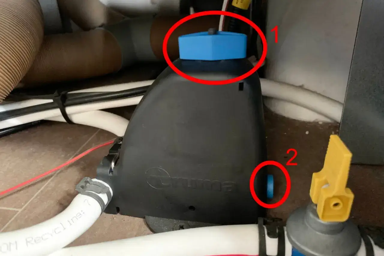 D&eacute;tail du syst&egrave;me de vidange chauffe eau camping car. Les points rouges indiquent les bouchons &agrave; retirer pour la vidange.
