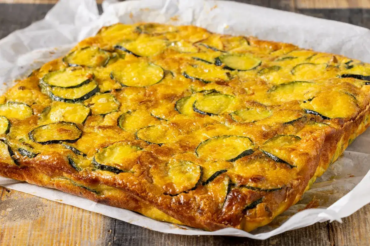 Frittata di zucchine dorata e invitante, con fette di zucchine ben visibili sulla superficie croccante.