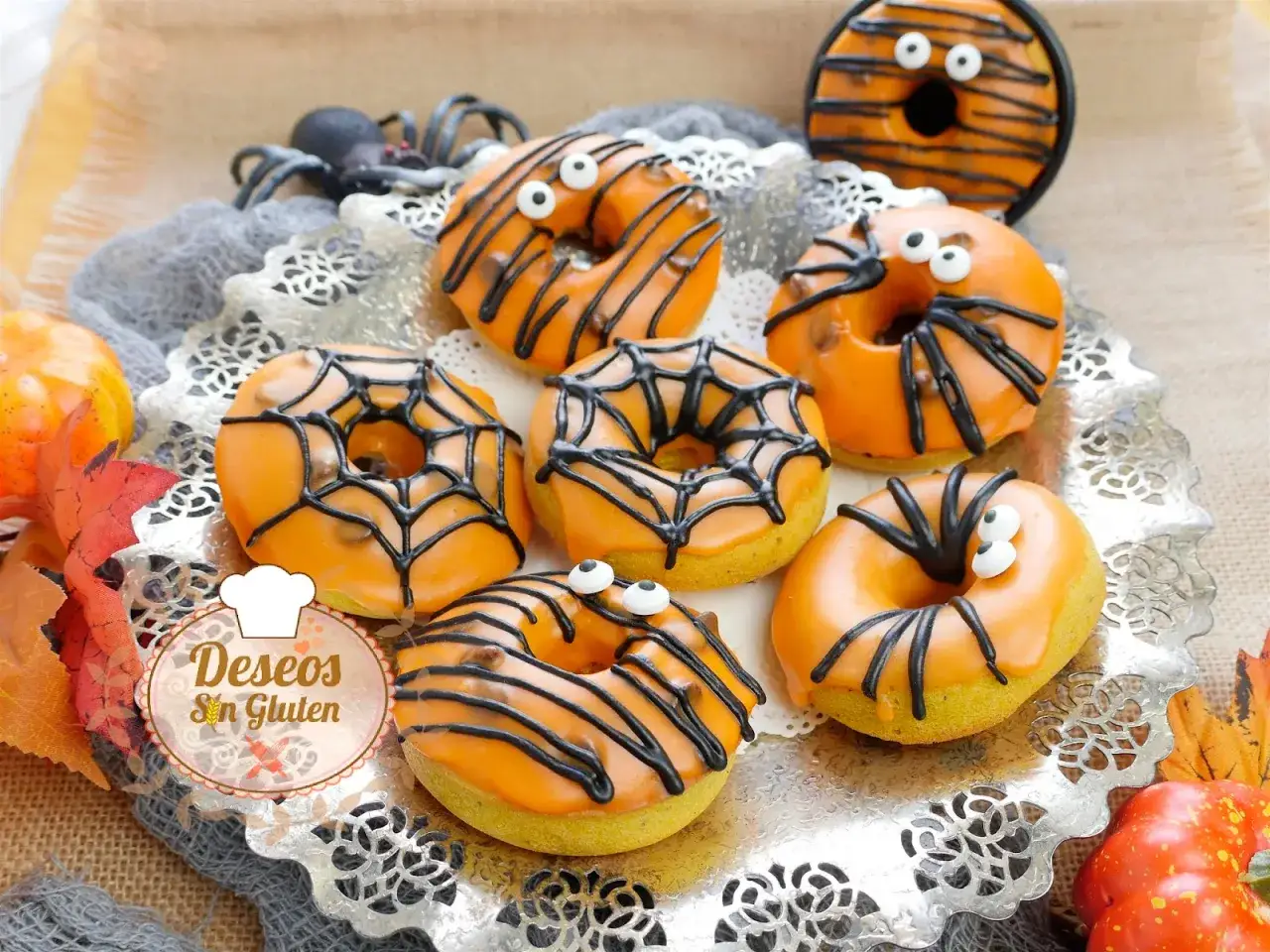 Deliciosos donuts de calabaza decorados para Halloween con telarañas, arañas y ojos saltones. ¡Perfectos para una fiesta espeluznante!