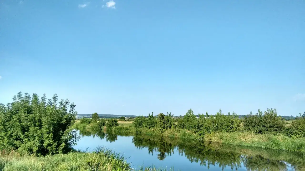 Spokojna rzeka odbija błękitne niebo i bujną zieleń. Idealne miejsce na odkrywanie ponidzie atrakcje.