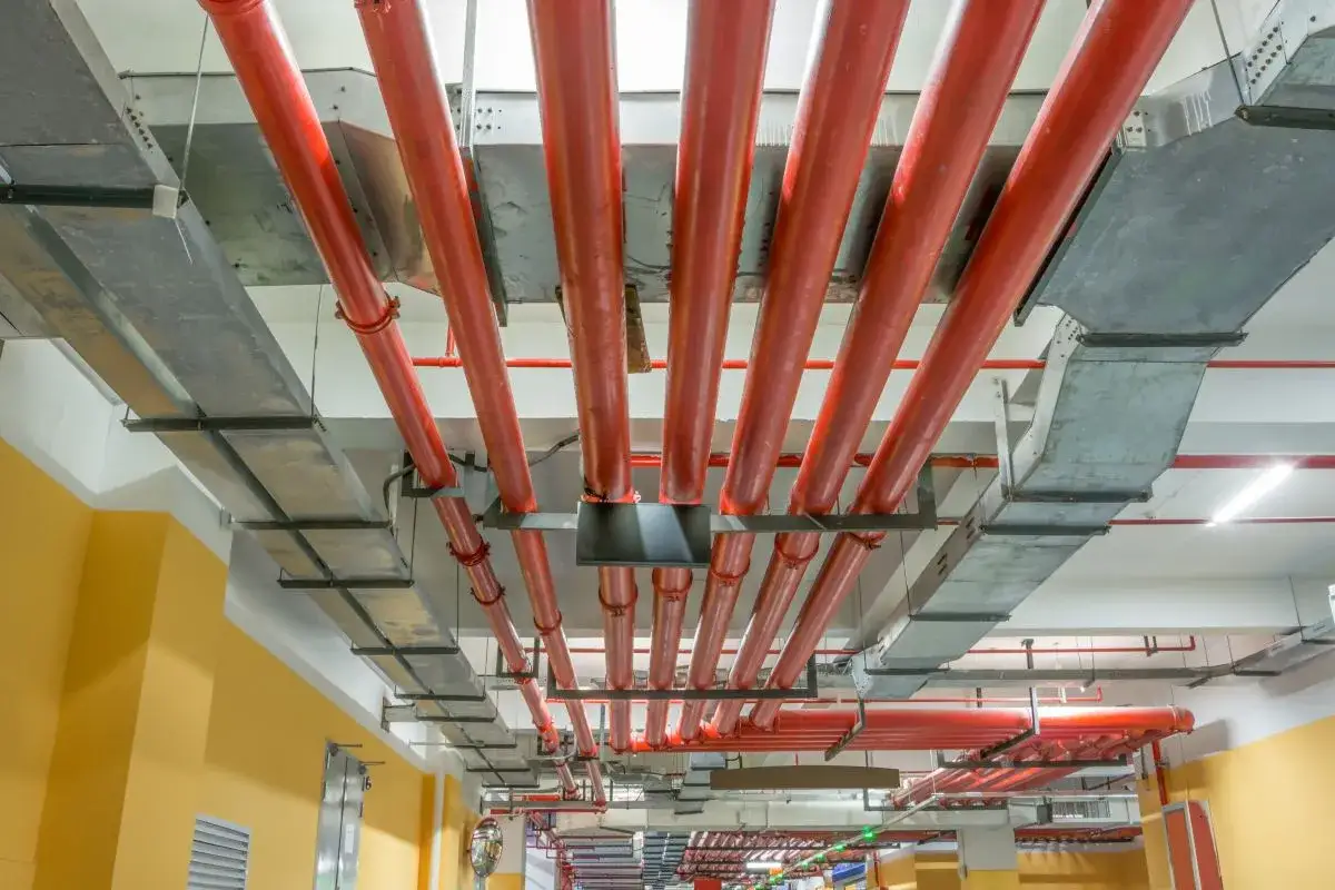 Sufit z systemem kanałów wentylacyjnych i czerwonymi rurami, stanowiącymi kluczowe instalacje ppoż.