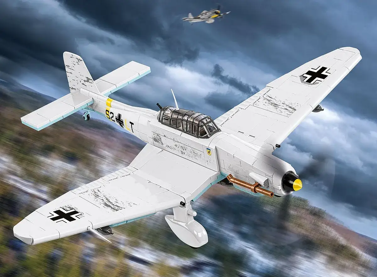 Ein weißes Stuka Flugzeug mit schwarzen Kreuzen fliegt durch dramatische Wolken. Ein weiteres Flugzeug ist am Himmel zu sehen.