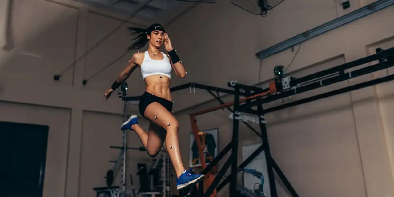 Kobieta w sportowym stroju, z markerami na ciele, analizuje swoją anatomię podczas biegu w laboratorium.