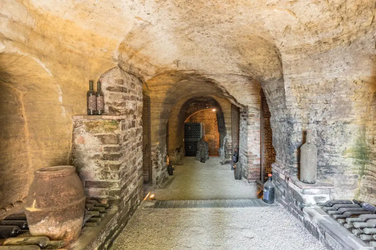 Antica cantina a volta, con bottiglie e anfora, nel cuore di Colle Santa Mustiola.