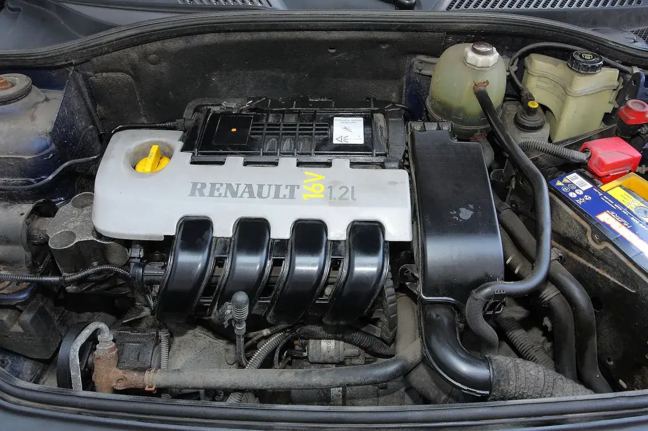 Silnik Renault Clio 3 1.2 benzyna. Widoczny osprzęt, przewody i pokrywa silnika z napisem RENAULT 16V 1.2L.